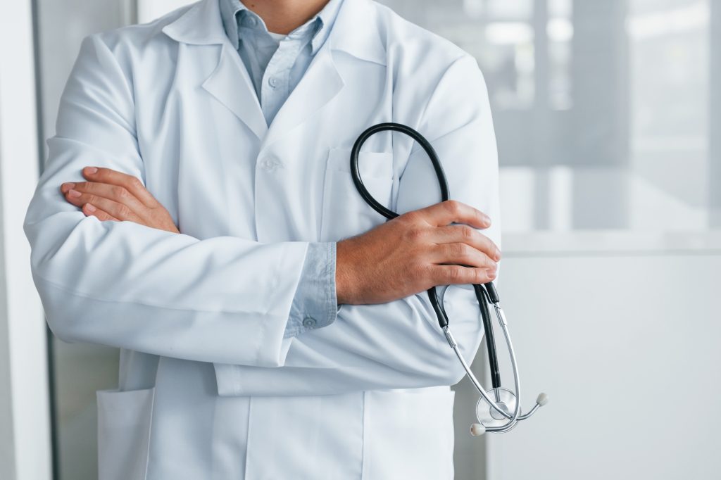 Stethoscope in hands. Professional medic in white coat is in the clinic